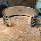 Wide silver cuff by Elvira Bill with repeating zigzag design, stamped accents, and detailed borders.