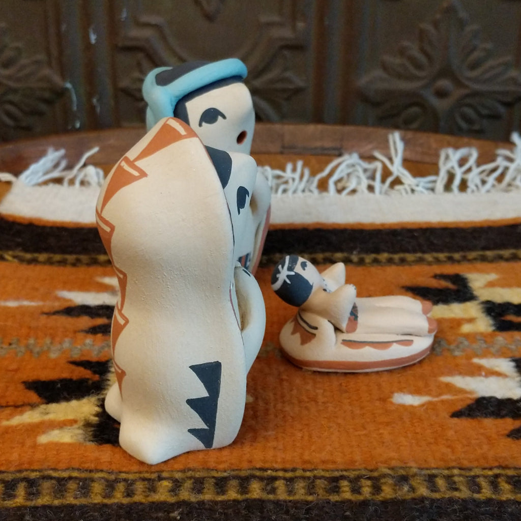 Clay sculpted into a small nativity scene and painted in the colors black, white, blue, and terracotta.