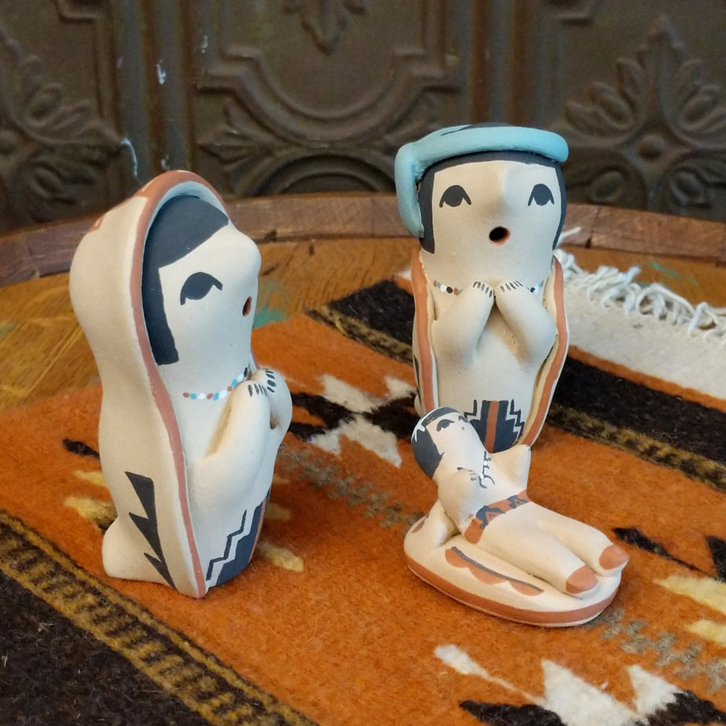 Clay sculpted into a small nativity scene and painted in the colors black, white, blue, and terracotta.