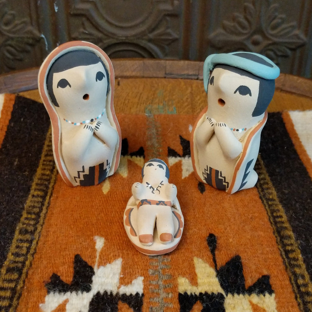 Clay sculpted into a small nativity scene and painted in the colors black, white, blue, and terracotta.