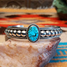 Sterling silver cuff bracelet with Kingman turquoise set in the round bezel and twisted rope with ornate silverwork accents.