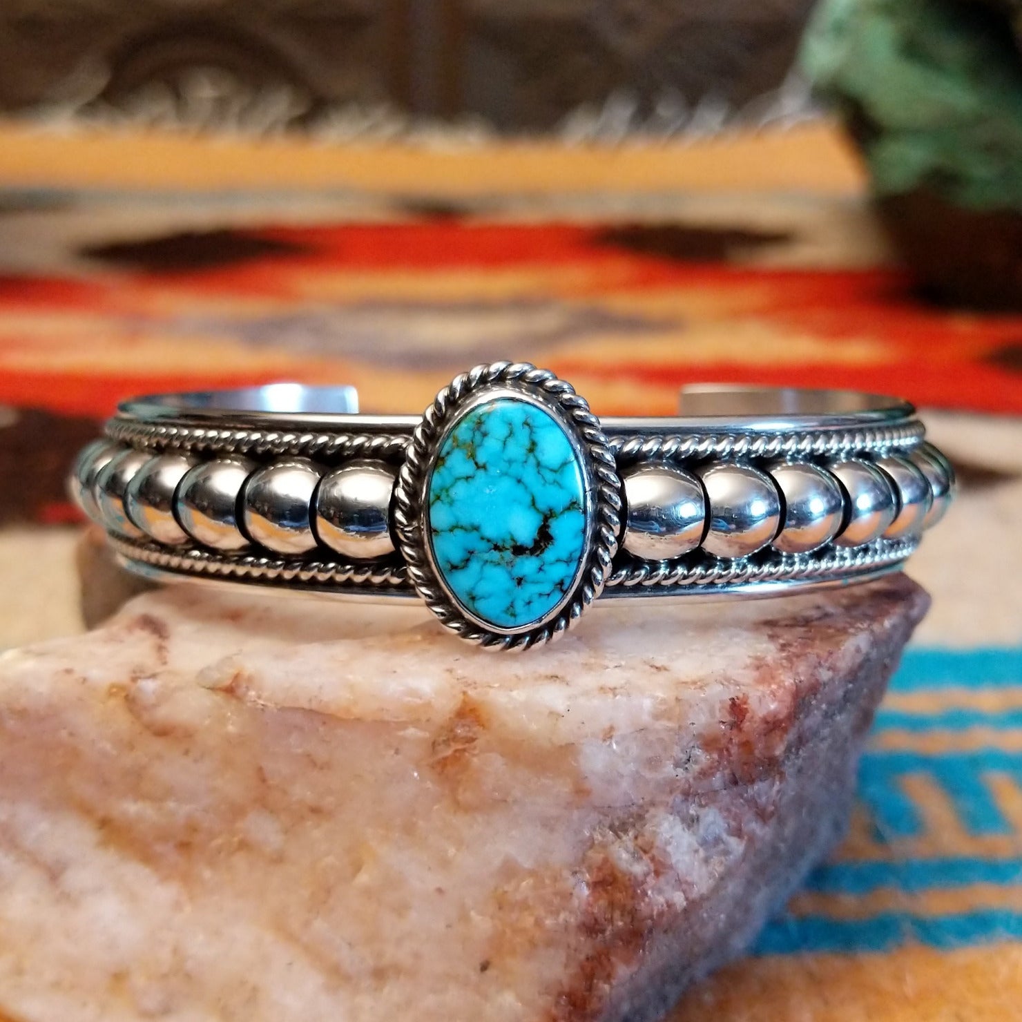 Sterling silver cuff bracelet with Kingman turquoise set in the round bezel and twisted rope with ornate silverwork accents.