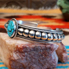 Sterling silver cuff bracelet with Kingman turquoise set in the round bezel and twisted rope with ornate silverwork accents.