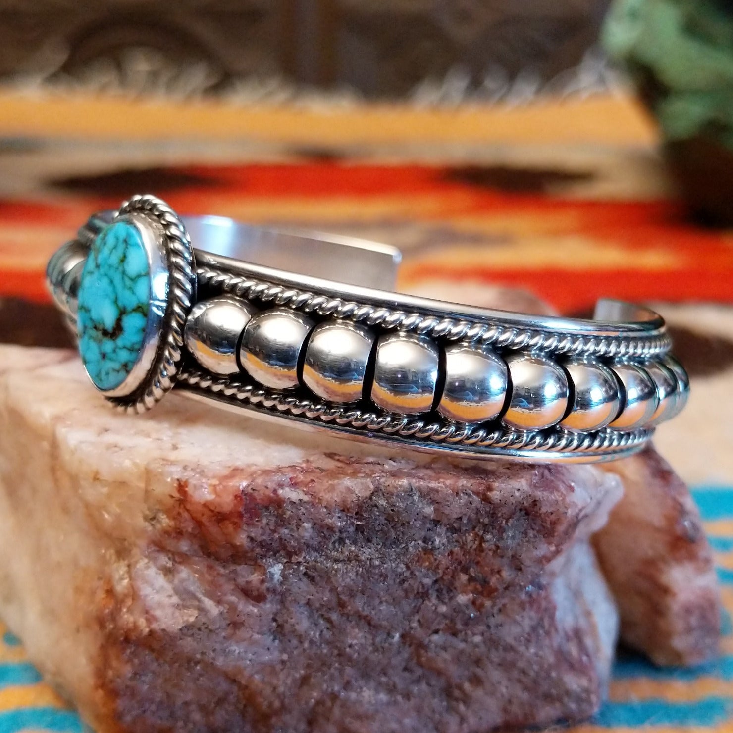 Sterling silver cuff bracelet with Kingman turquoise set in the round bezel and twisted rope with ornate silverwork accents.