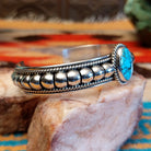 Sterling silver cuff bracelet with Kingman turquoise set in the round bezel and twisted rope with ornate silverwork accents.