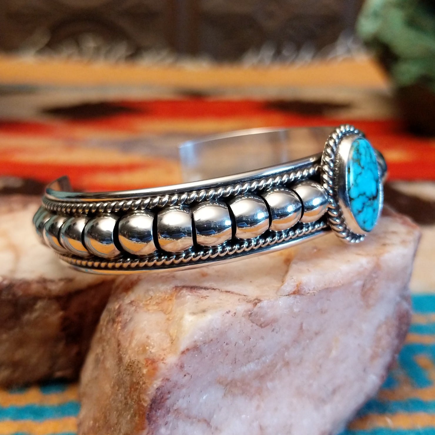 Sterling silver cuff bracelet with Kingman turquoise set in the round bezel and twisted rope with ornate silverwork accents.