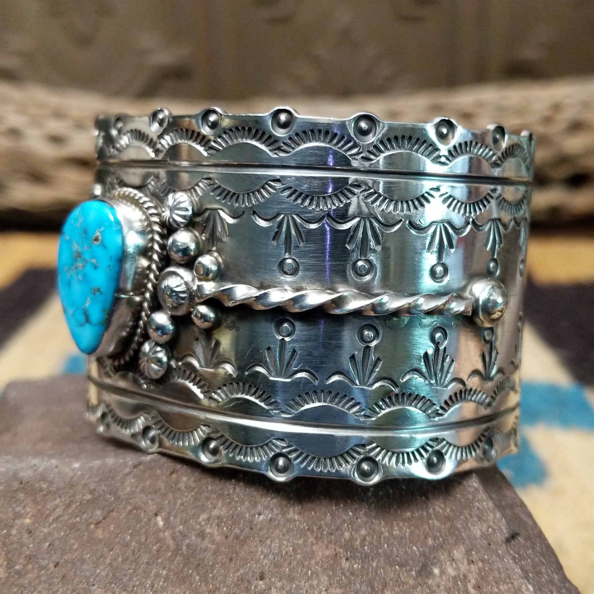 Kingman turquoise cuff by Betty A. Lee featuring a natural blue turquoise stone on a wide hand-stamped sterling silver cuff; side view.