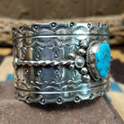 Kingman turquoise cuff by Betty A. Lee featuring a natural blue turquoise stone on a wide hand-stamped sterling silver cuff; side view.