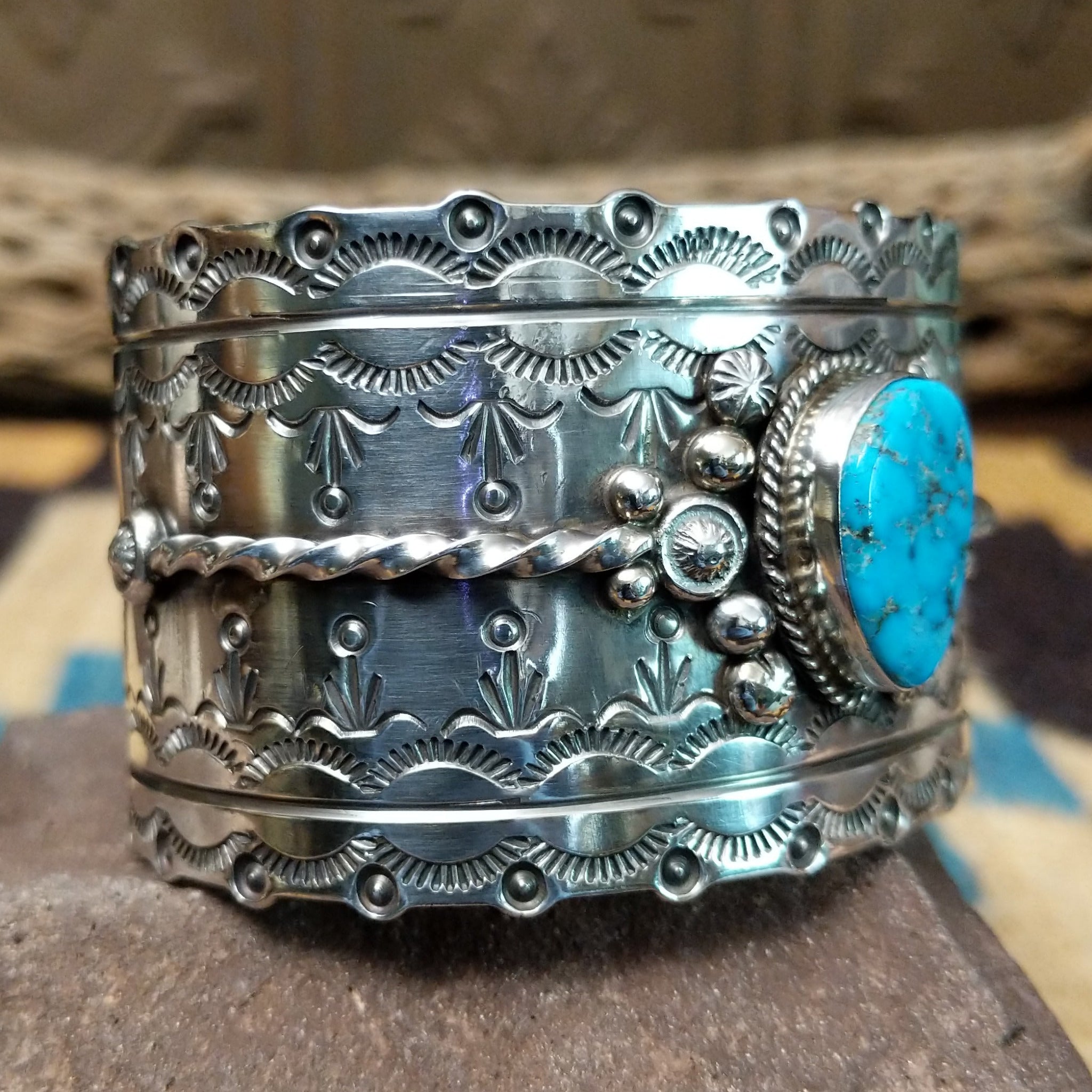 Kingman turquoise cuff by Betty A. Lee featuring a natural blue turquoise stone on a wide hand-stamped sterling silver cuff; side view.