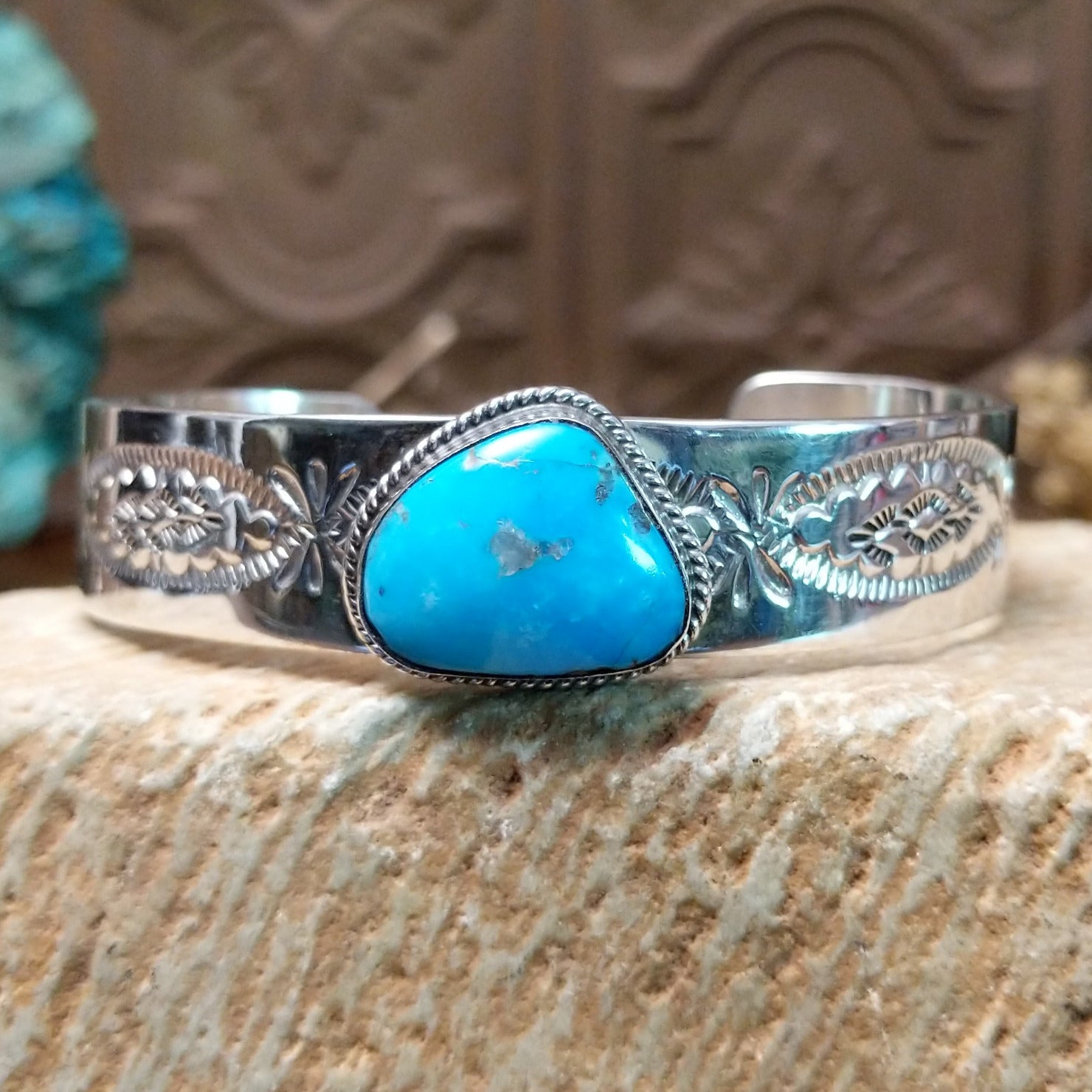 Sterling silver bracelet with turquoise set in the bezel, framed by twisted rope accents and stamping along the polished band.