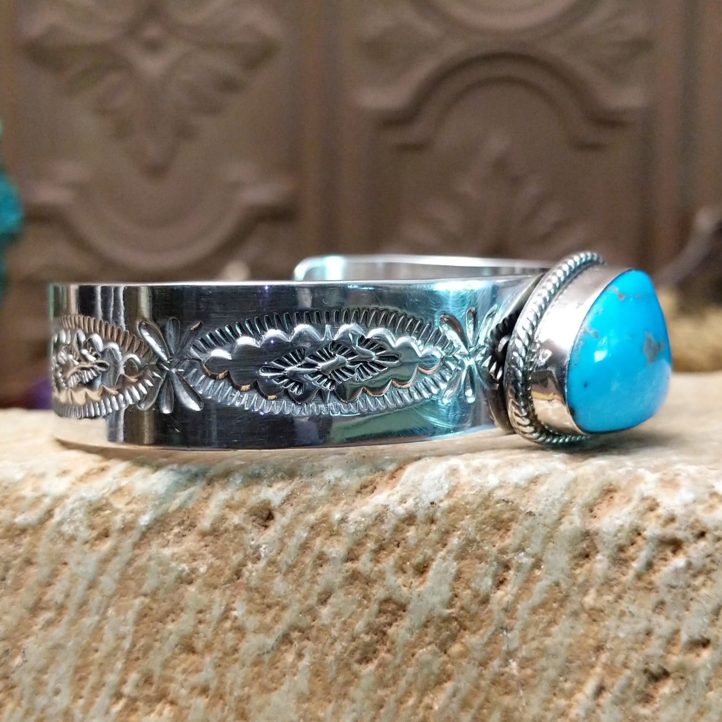Sterling silver bracelet with turquoise set in the bezel, framed by twisted rope accents and stamping along the polished band.