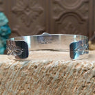 Sterling silver bracelet with turquoise set in the bezel, framed by twisted rope accents and stamping along the polished band.
