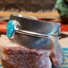 Sterling silver cuff bracelet with Kingman turquoise set in an oval bezel and feather band design.