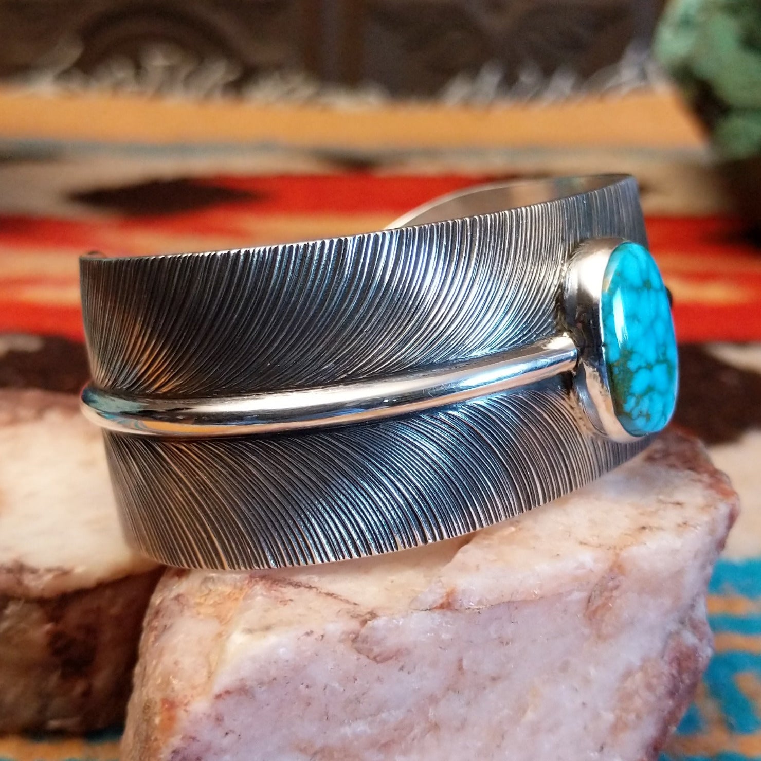 Sterling silver cuff bracelet with Kingman turquoise set in an oval bezel and feather band design.