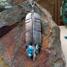 Kingman Turquoise feather pendant by Lena Platero featuring a detailed silver feather with etched texture, polished accents, and an oval turquoise stone with dark matrix.