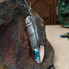 Kingman Turquoise feather pendant by Lena Platero featuring a detailed silver feather with etched texture, polished accents, and an oval turquoise stone with dark matrix; side view.