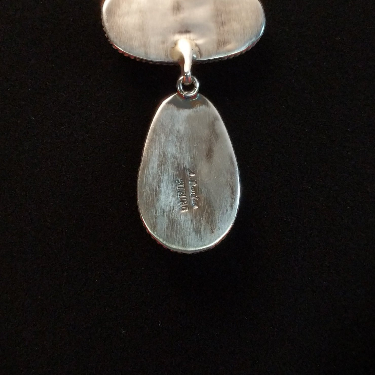 The artisan's signature is found on the sterling silver backing of the necklace. 