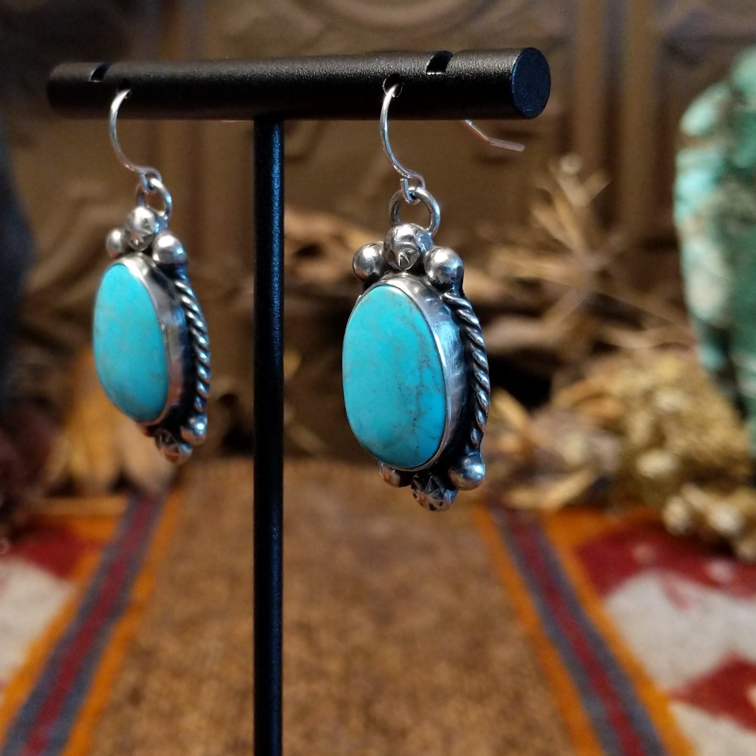 Sterling silver earrings with kingman turquoise set in the bezels, framed by twisted rope and dotted accents.