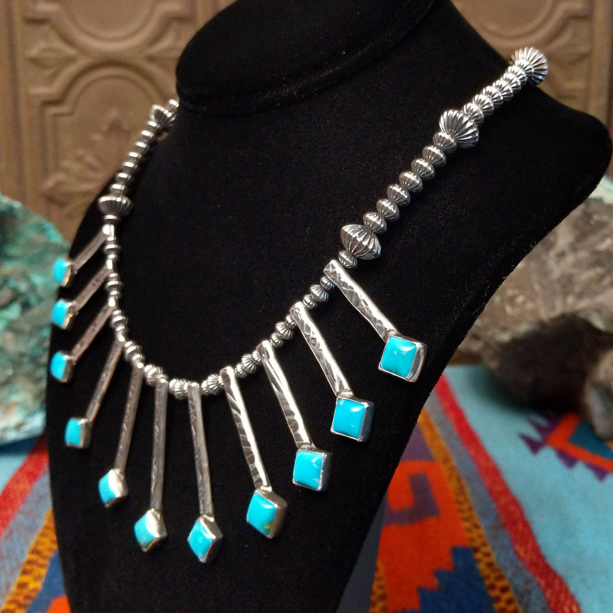 Everett & Mary Teller Kingman Turquoise necklace featuring vibrant turquoise stones, stamped Sterling Silver drops, and decorative silver beads; side view.