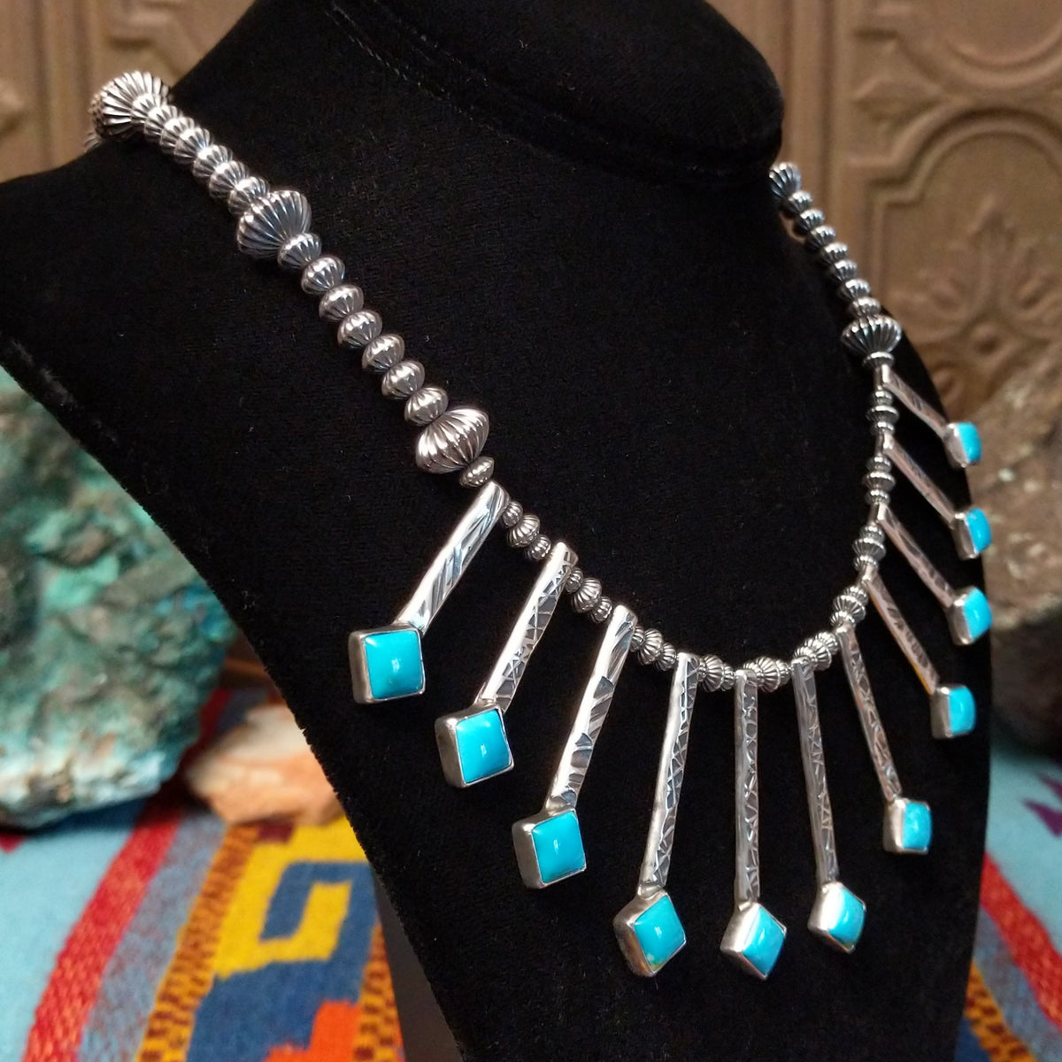 Everett & Mary Teller Kingman Turquoise necklace featuring vibrant turquoise stones, stamped Sterling Silver drops, and decorative silver beads; side view.