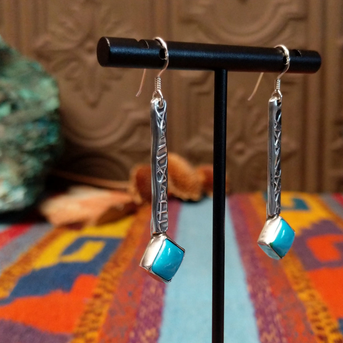 Everett & Mary Teller Kingman Turquoise earrings featuring vibrant turquoise stones, stamped Sterling Silver drops, and decorative silver beads; side view.