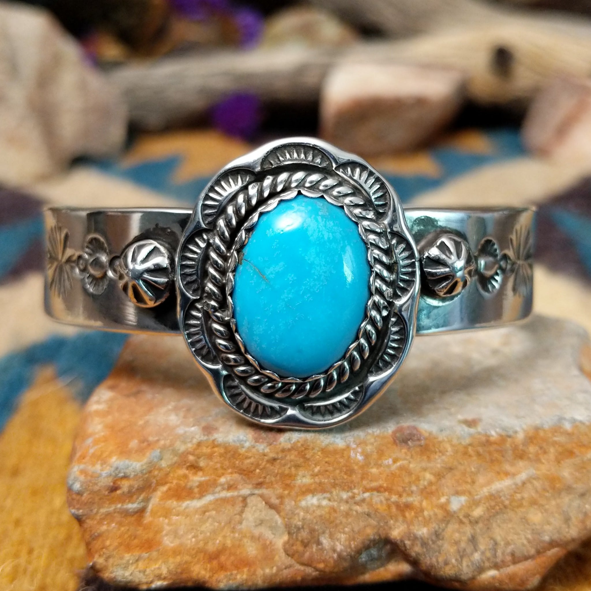 Handcrafted sterling silver Navajo cuff by Charlene & Robert Little featuring an oval Kingman turquoise cabochon with a twisted rope bezel, scalloped silver border, and hand-stamped concho accents.