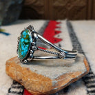 Kingman turquoise cuff by Murphy Platero featuring a large oval blue and green matrix stone framed by decorative silver beads, stamped accents, and an open split-band design; side view.