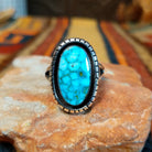 Kingman Turquoise Shadowbox Ring featuring a large oval blue turquoise stone with natural matrix, set in sterling silver with an oxidized shadowbox setting, notched border, and split-shank band.