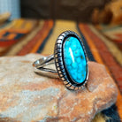 Kingman Turquoise Shadowbox Ring featuring a large oval blue turquoise stone with natural matrix, set in sterling silver with an oxidized shadowbox setting, notched border, and split-shank band; side view.