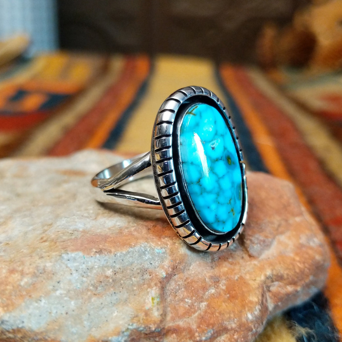 Kingman Turquoise Shadowbox Ring featuring a large oval blue turquoise stone with natural matrix, set in sterling silver with an oxidized shadowbox setting, notched border, and split-shank band; side view.