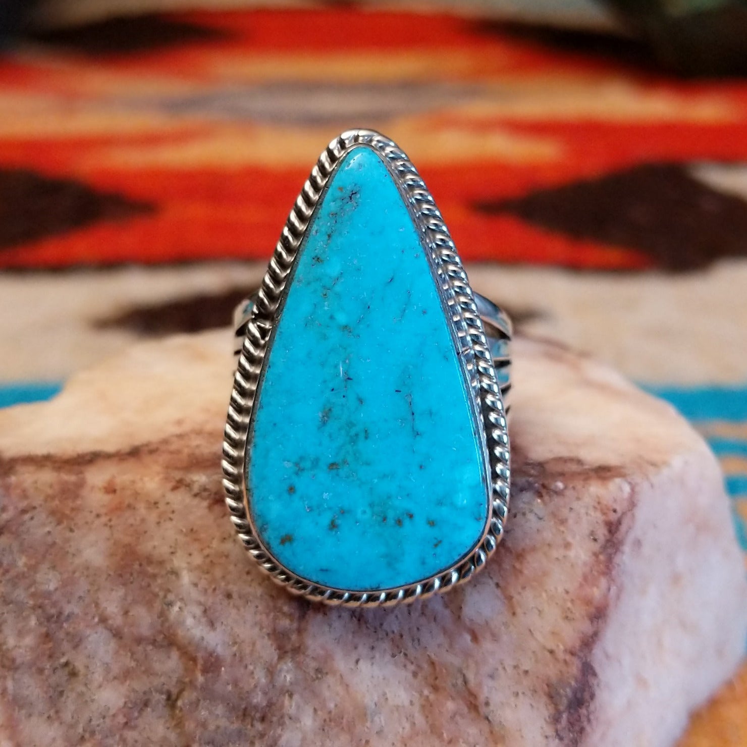 Sterling silver ring with Kingman turquoise set in round-triangle bezel, framed by twisted rope accents.