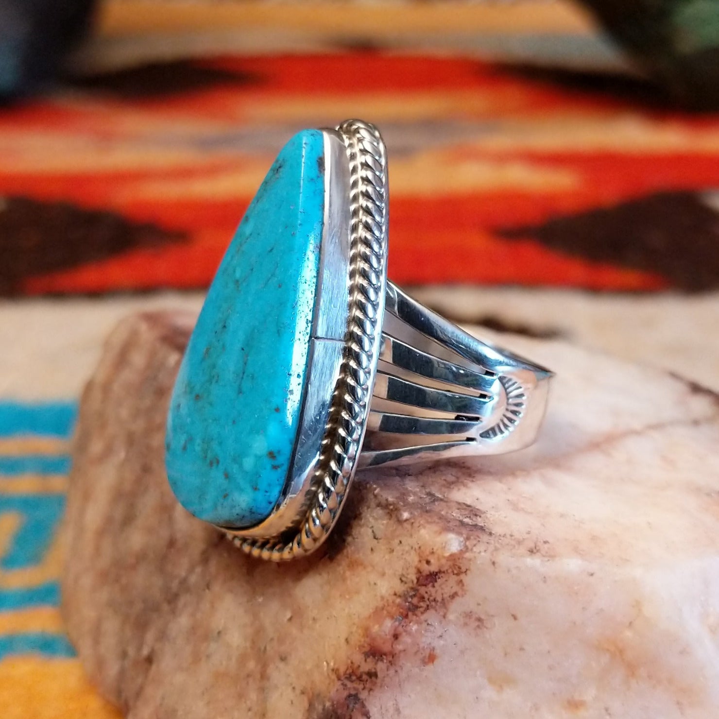 Sterling silver ring with Kingman turquoise set in round-triangle bezel, framed by twisted rope accents.