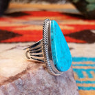Sterling silver ring with Kingman turquoise set in round-triangle bezel, framed by twisted rope accents.