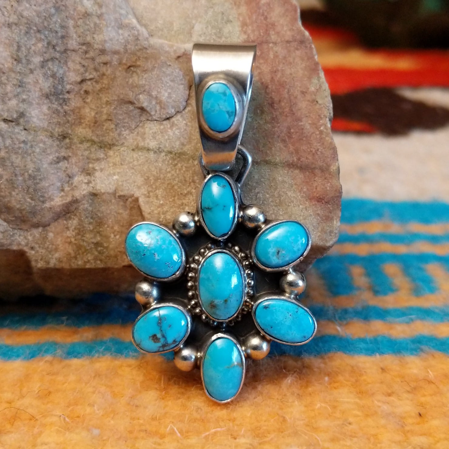 Sterling silver pendant with Kingman turquoise set in oval bezels that create a starburst design.