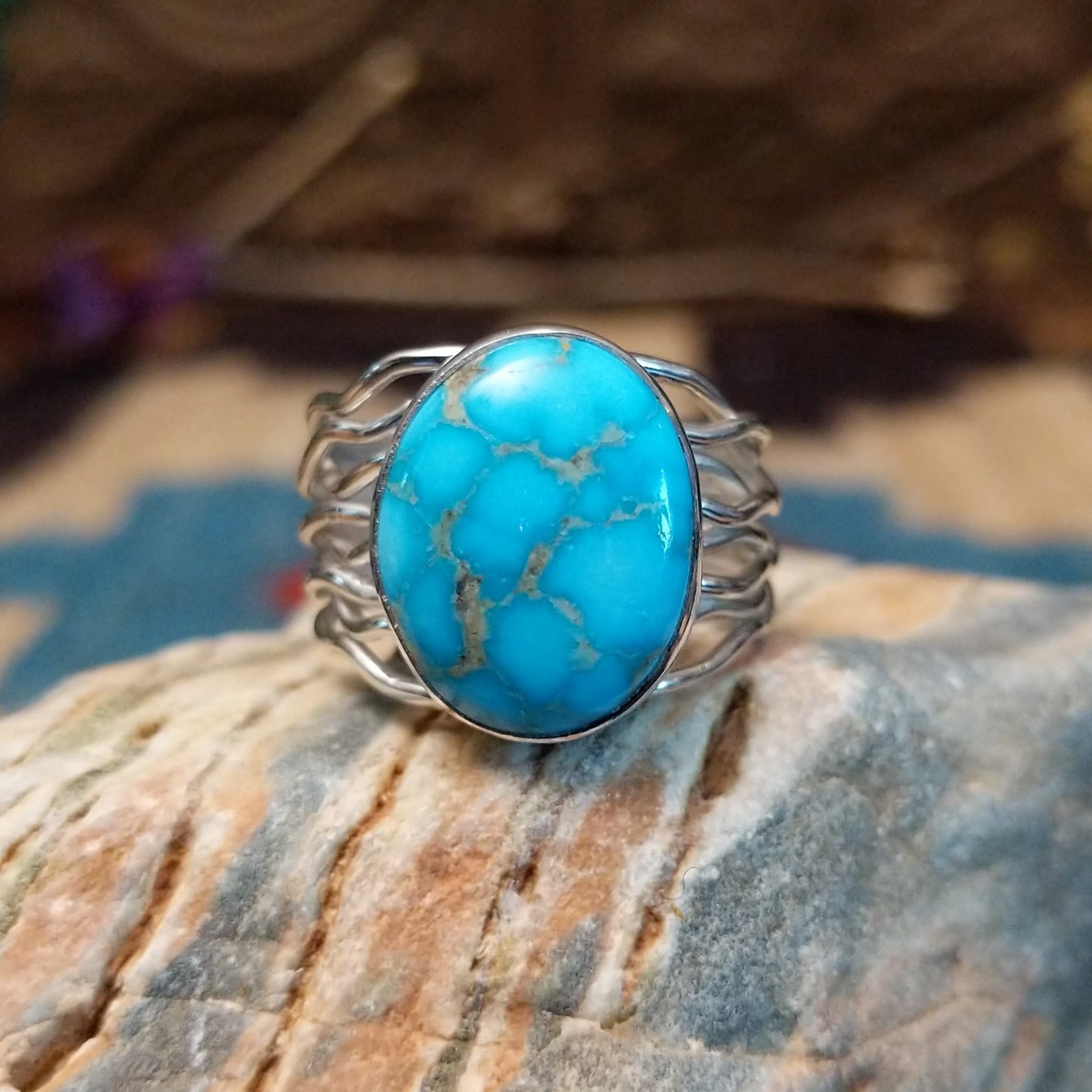 Sterling silver ring with Kingman turquoise set in a round bezel and strands of silver making up the band.