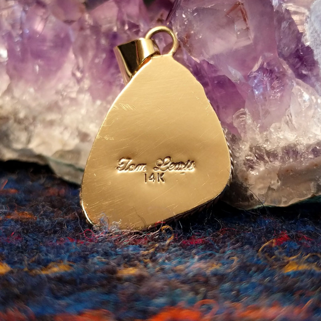 The back of the pendant features the artist's signature and gold stamp.