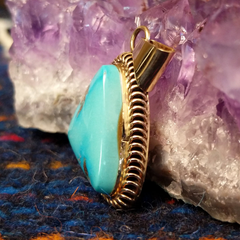 Kingman turquoise triangular gold pendant with a gold coil bezel.