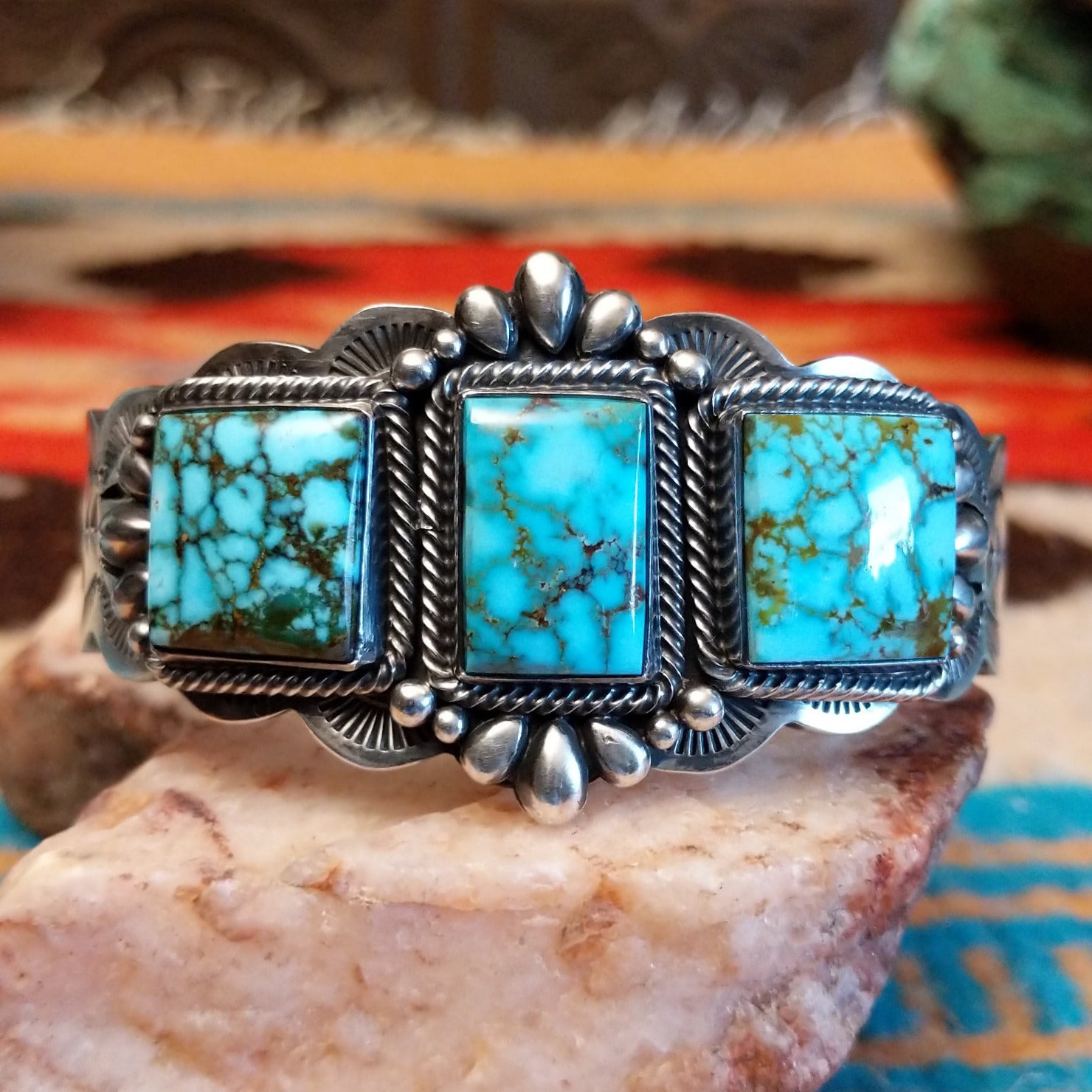 This sterling silver cuff bracelet features Kingman turquoise set in square bezels, framed by twisted rope and unique silverwork accents.
