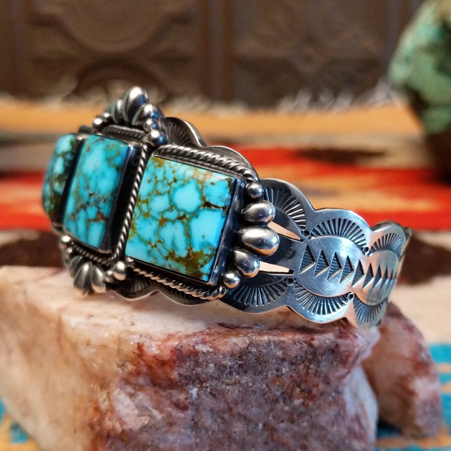 This sterling silver cuff bracelet features Kingman turquoise set in square bezels, framed by twisted rope and unique silverwork accents.