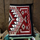 Klagetoh Navajo rug by Adele Mike with a red, black, ivory, and gray geometric pattern framed by a black border.