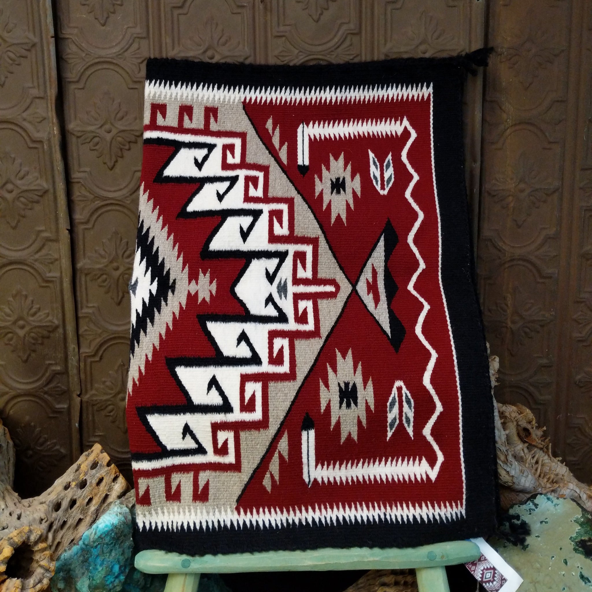 Klagetoh Navajo rug by Adele Mike with a red, black, ivory, and gray geometric pattern framed by a black border.