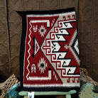 Klagetoh Navajo rug by Adele Mike with a red, black, ivory, and gray geometric pattern framed by a black border.