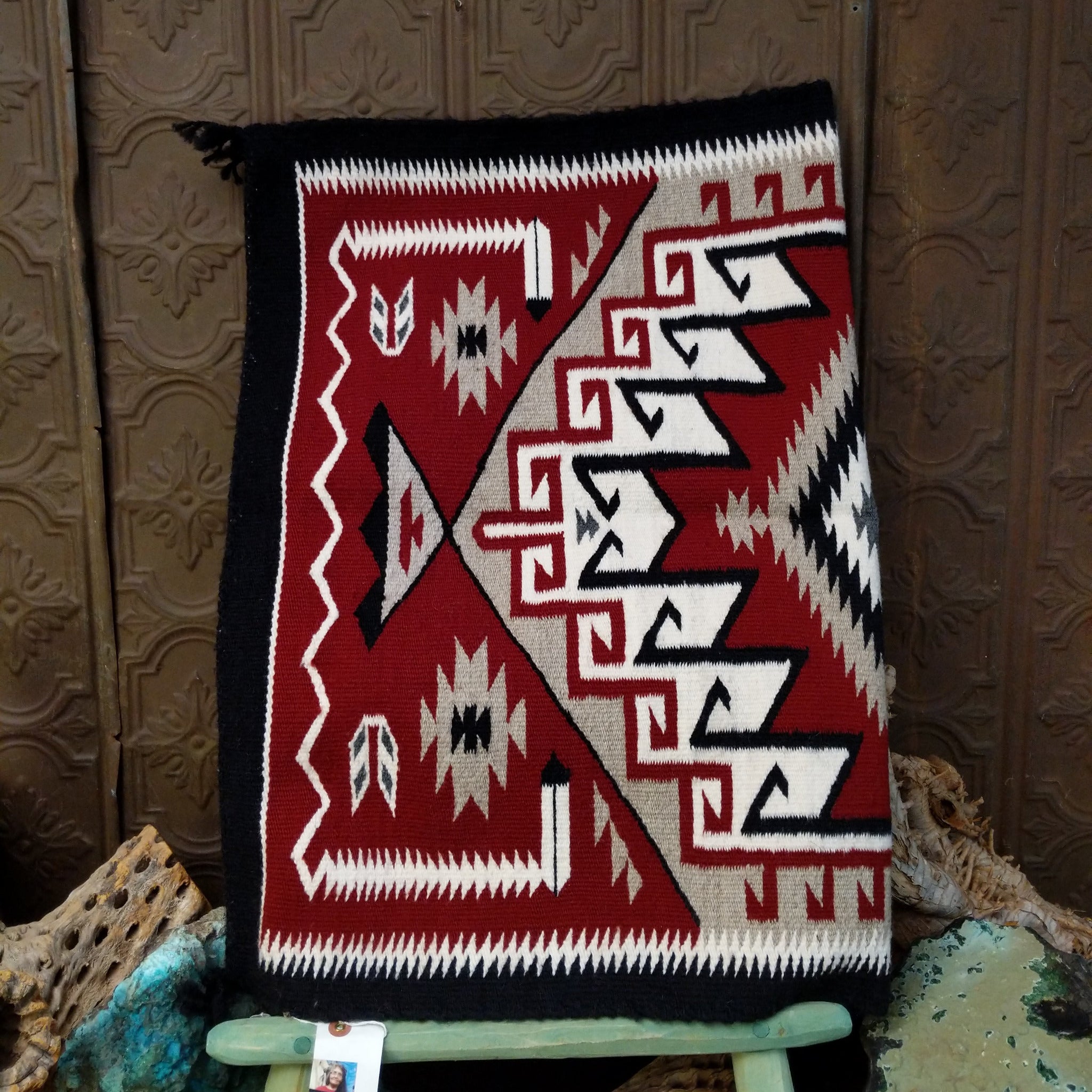 Klagetoh Navajo rug by Adele Mike with a red, black, ivory, and gray geometric pattern framed by a black border.