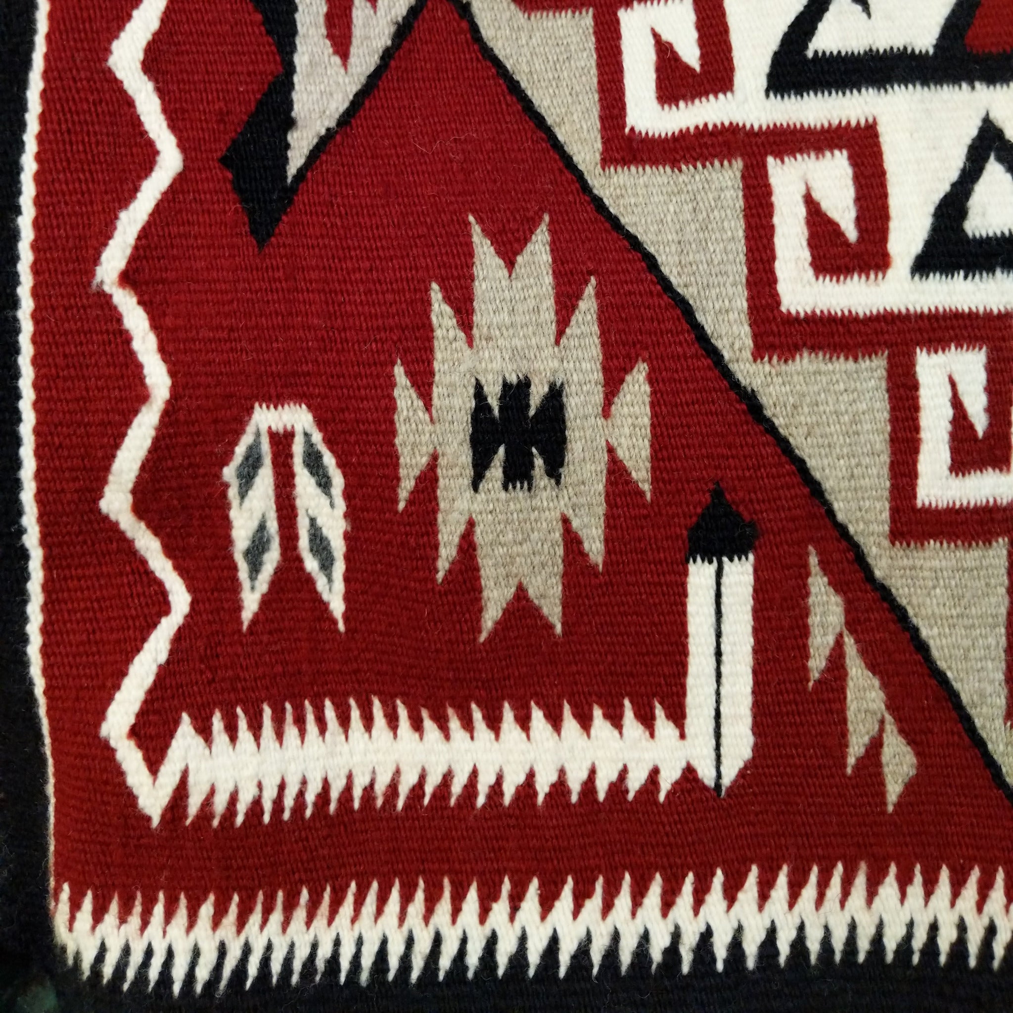 Klagetoh Navajo rug by Adele Mike with a red, black, ivory, and gray geometric pattern framed by a black border.