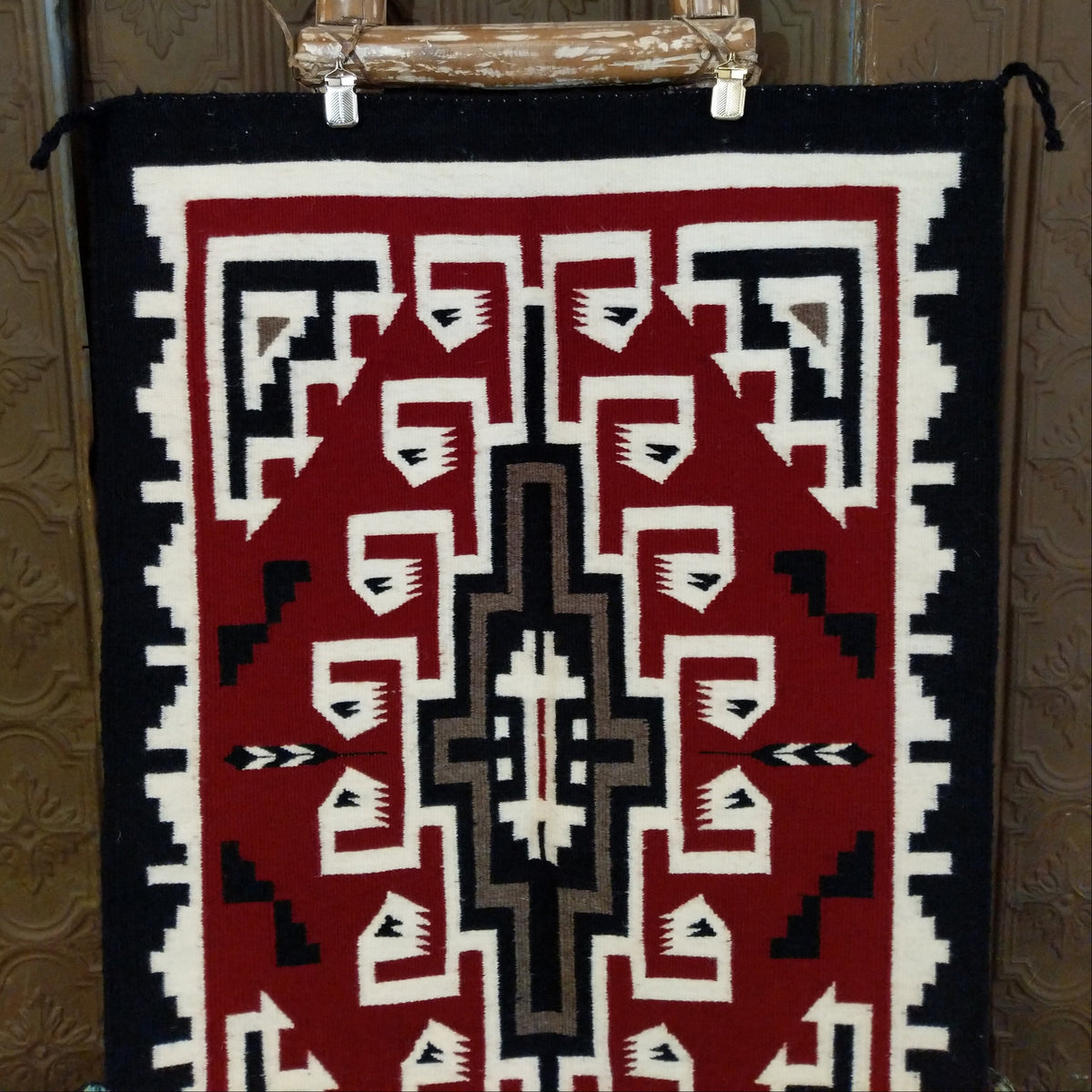This handmade Navajo rug by Irene Eskee features a central motif with intricate geometric designs emanating outward.