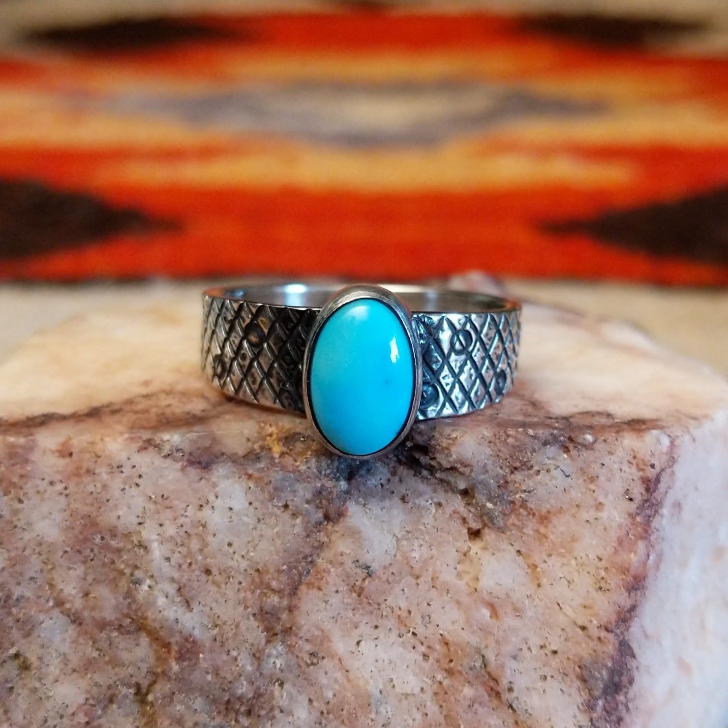 Sterling silver ring with Kingman turquoise set in the oval bezel, featuring a stamped, knurled band.