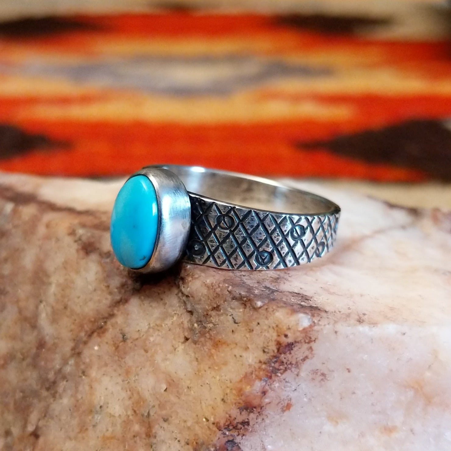 Sterling silver ring with Kingman turquoise set in the oval bezel, featuring a stamped, knurled band.