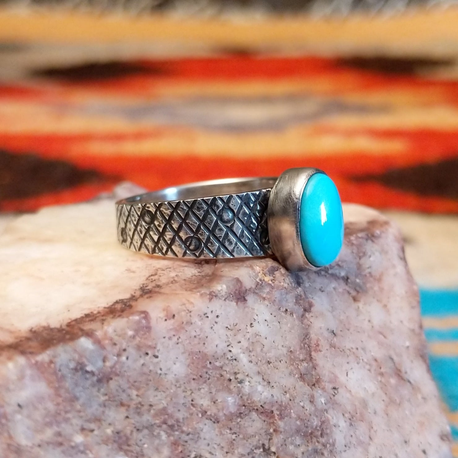 Sterling silver ring with Kingman turquoise set in the oval bezel, featuring a stamped, knurled band.