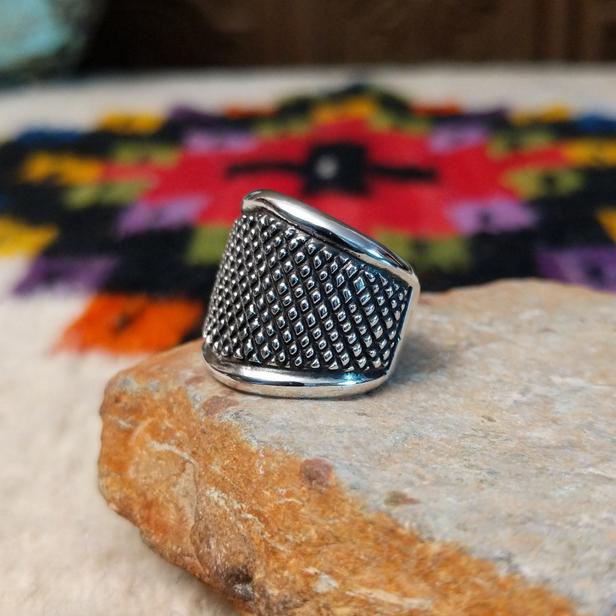 This distinctive Silver Ring by Raymond Coriz features a wide silver band with a raised crosshatch pattern, oxidized detailing, and smooth polished borders along the top and bottom; side view.
