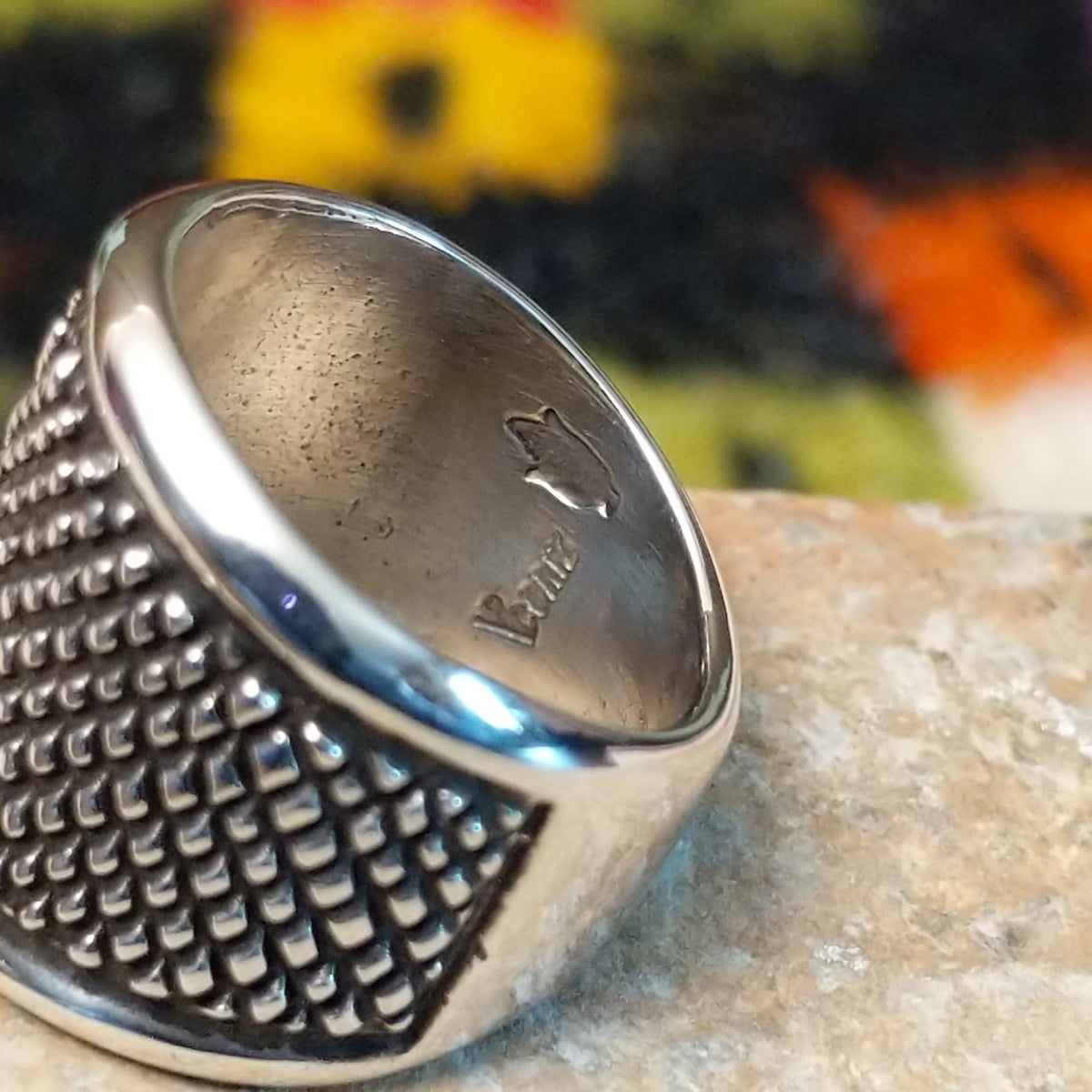 This distinctive Silver Ring by Raymond Coriz features a wide silver band with a raised crosshatch pattern, oxidized detailing, and smooth polished borders along the top and bottom; artisan and Sterling Silver stamp.